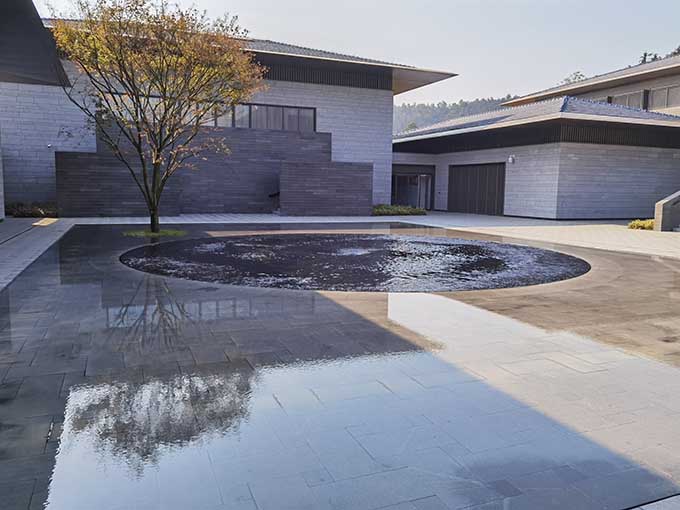 灰墙建筑、树木与镜面水景
